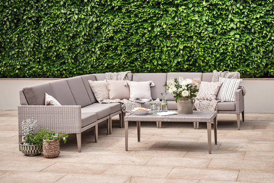 Rattan modular garden sofa in beige sitting on patio.